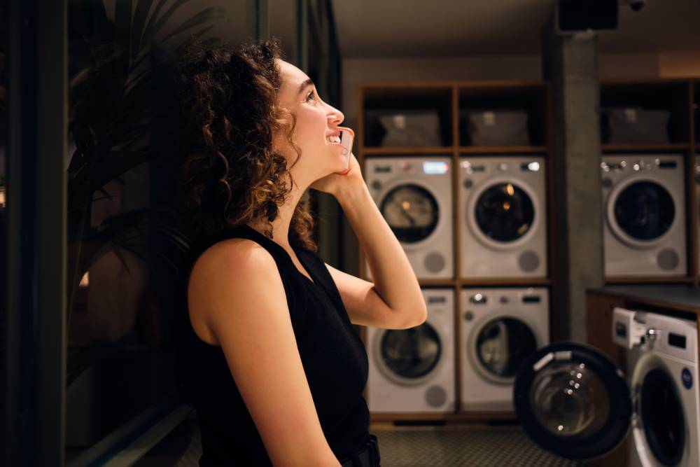 Woman talking on the phone at a self-service laundromat at night