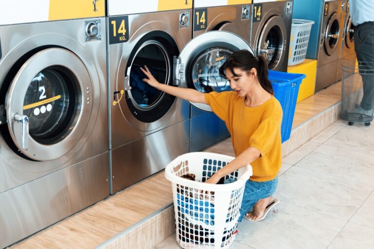 Customer placing clothes into washer at Wash Em Up in Midland