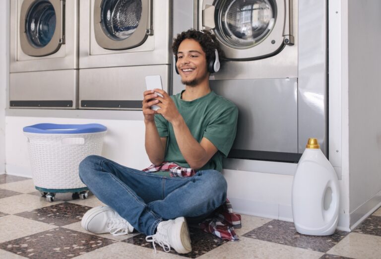 Man using phone while doing laundry at Midland laundromat