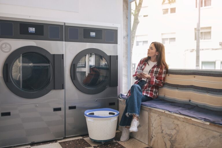 Woman waiting with laundry basket at affordable laundromat in Midland