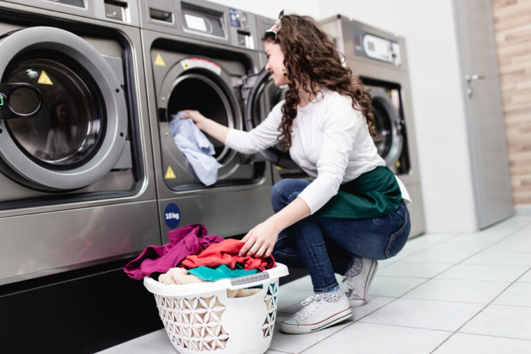 Woman loading clothes into washer at clean laundromat